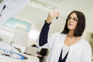 Picture of a female Lab Tech holding a vial of blood in a lab.