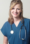 This is a picture of a nurse standing by a wall smiling.